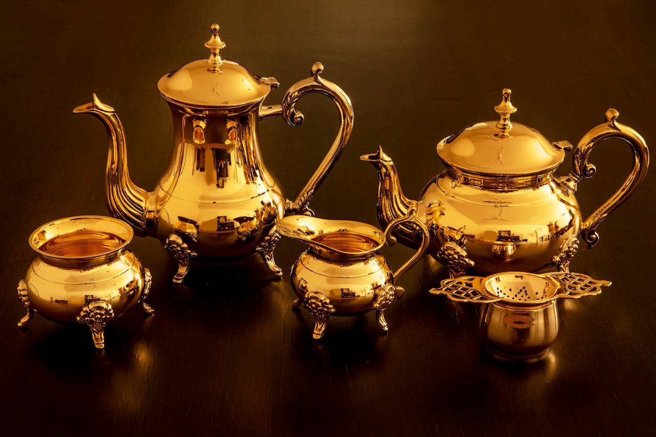 A luxurious golden teapot set with intricate designs beautifully arranged on a dark surface.